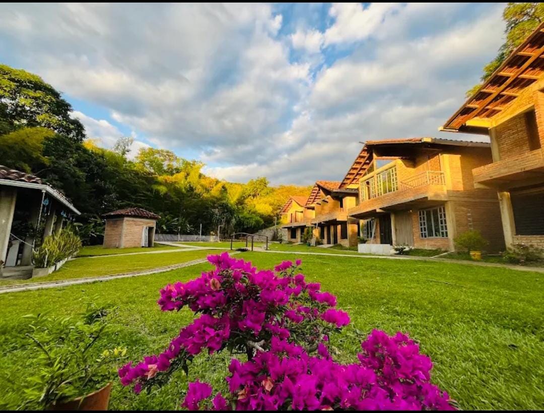 Cabañas de Wailele en ladrillo rodeadas de jardín con buganvilias al atardecer