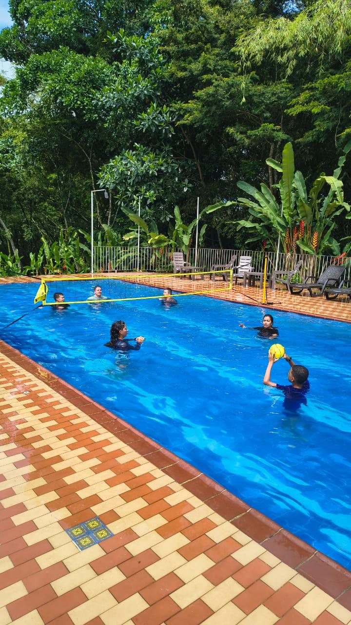 Piscina de Wailele con red de voleibol rodeada de naturaleza
